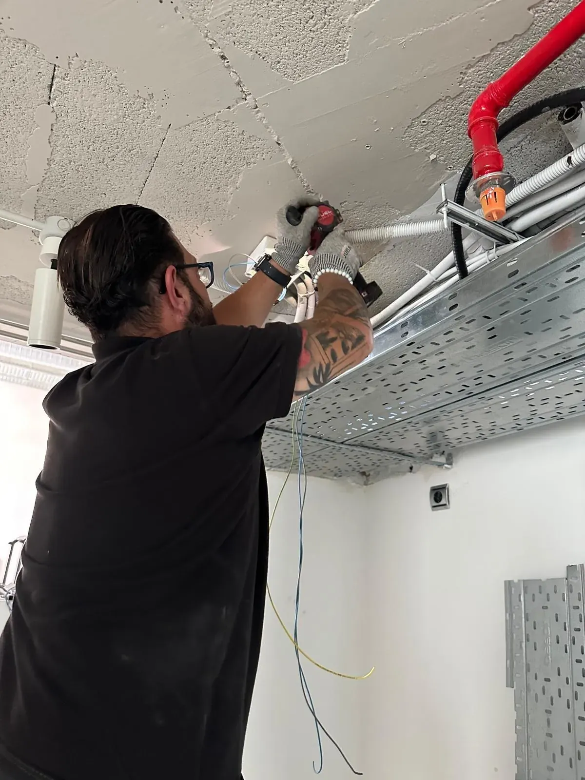 Néstor Márquez pasando cableado junto a una bandeja portacables en el techo