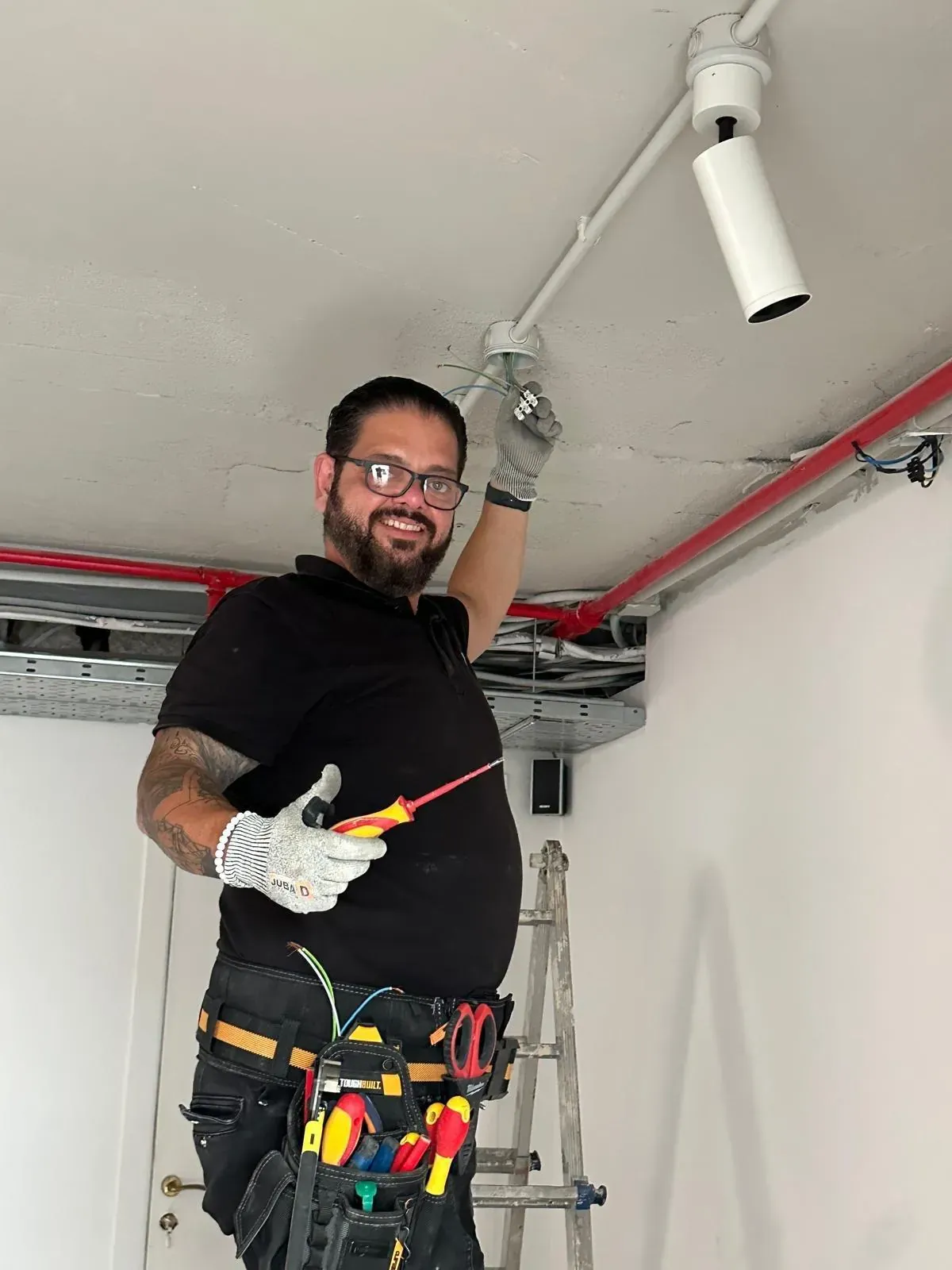 Néstor Márquez, electricista, conectando un punto de luz en el techo con el destornillador en la mano