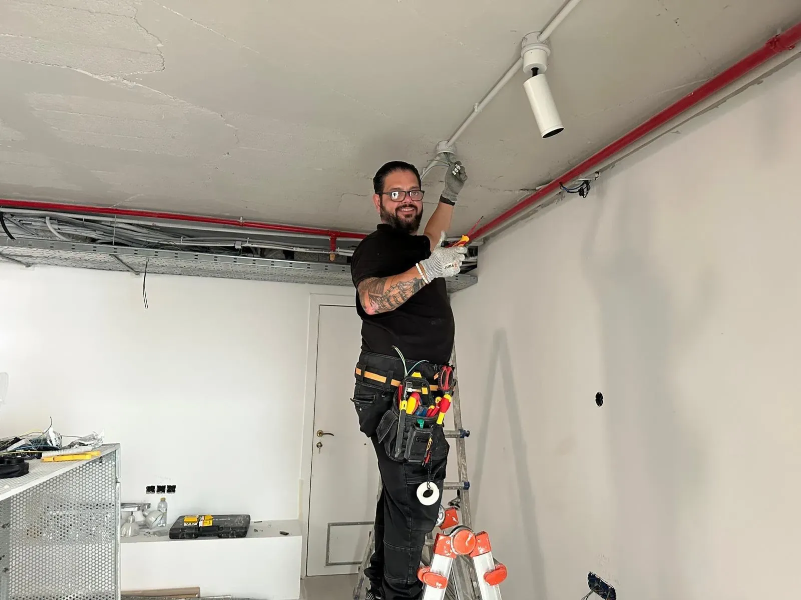 Néstor Márquez subido a una escalera trabajando en la instalación eléctrica del techo de un local